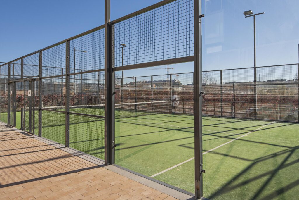 Padel court with tempered glass sidewalls and matte black structure, integrated LED lighting